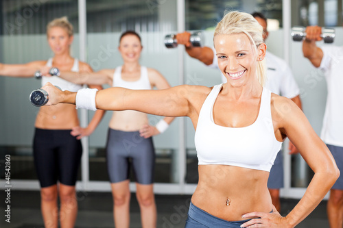 group of people exercise in gym with dumbbells
