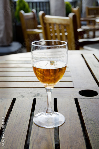 Glass of beer on a wooden table on an outdoor patio photo