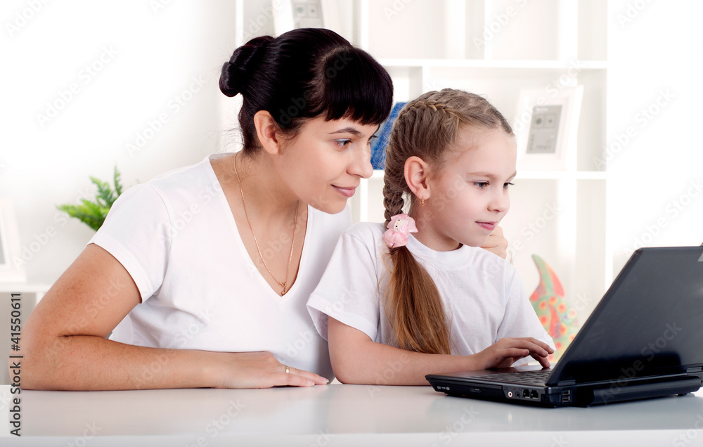 Mom and daughter are working together for a laptop Mom and daughter are working together for a laptop