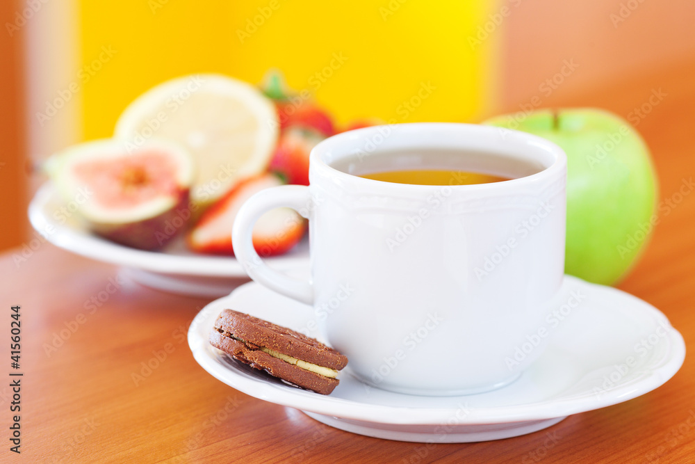cup of tea,cookie,apple, lemon, fig and strawberries on a plate cup of tea,cookie,apple, lemon, fig and strawberries on a plate