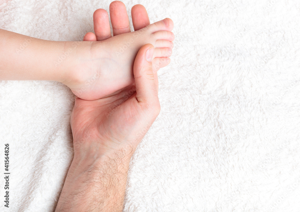 Father gently hold baby's leg Father gently hold baby's leg