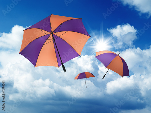Umbrella's falling from a blue sky with white Cumulus Clouds