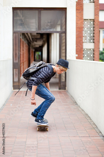 teen boy skateboarding in school passage