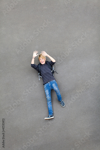 overhead view of a playful teen boy lying on ground