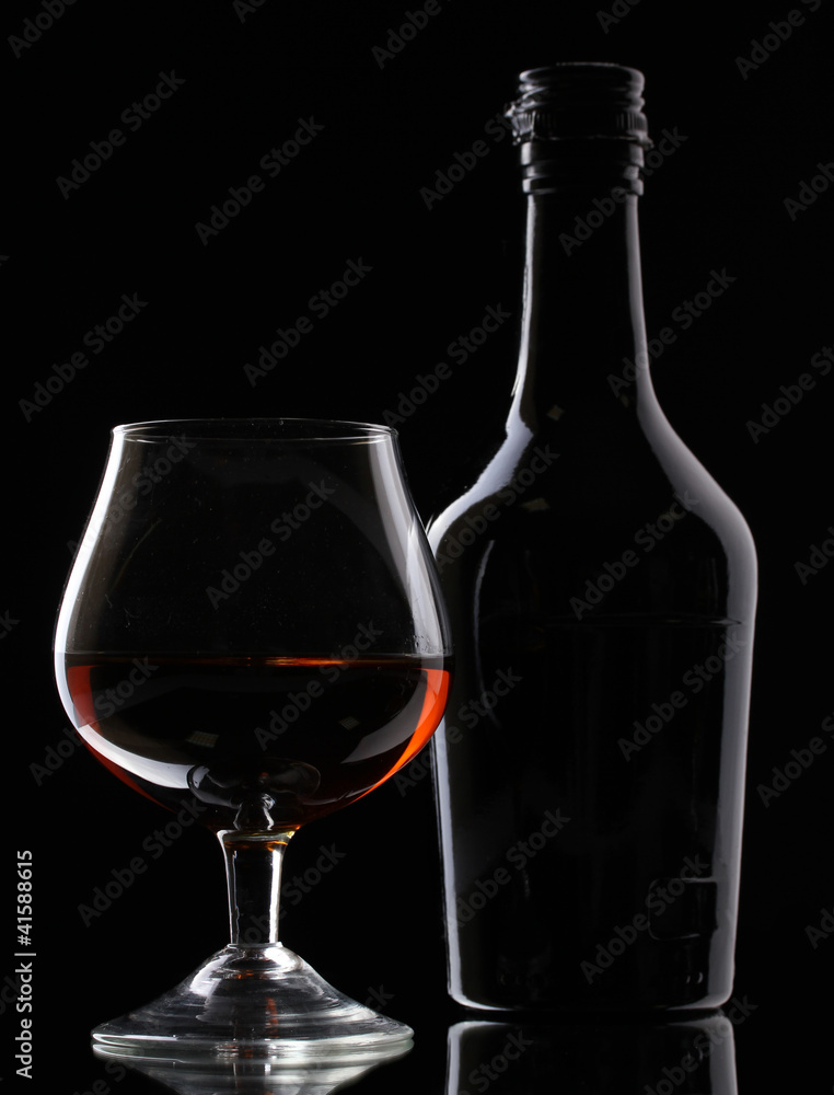 Glass of brandy and bottle on black background Glass of brandy and bottle on black background