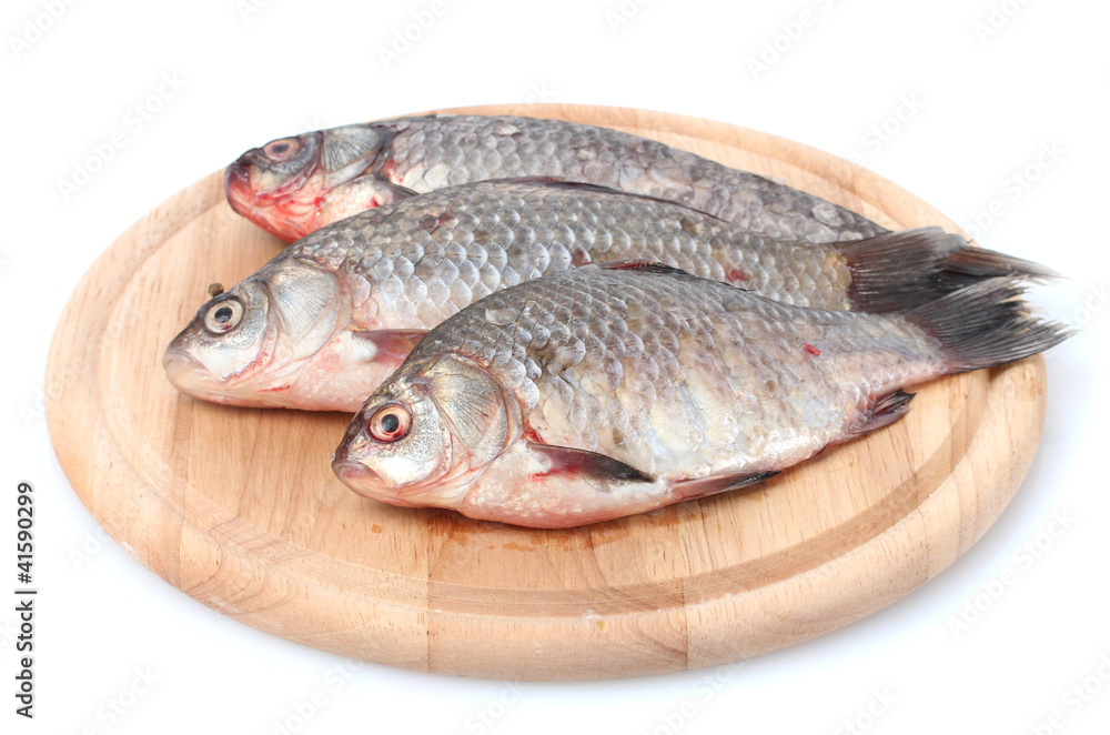 Fresh fishes on wooden cutting board isolated on white Fresh fishes on wooden cutting board isolated on white