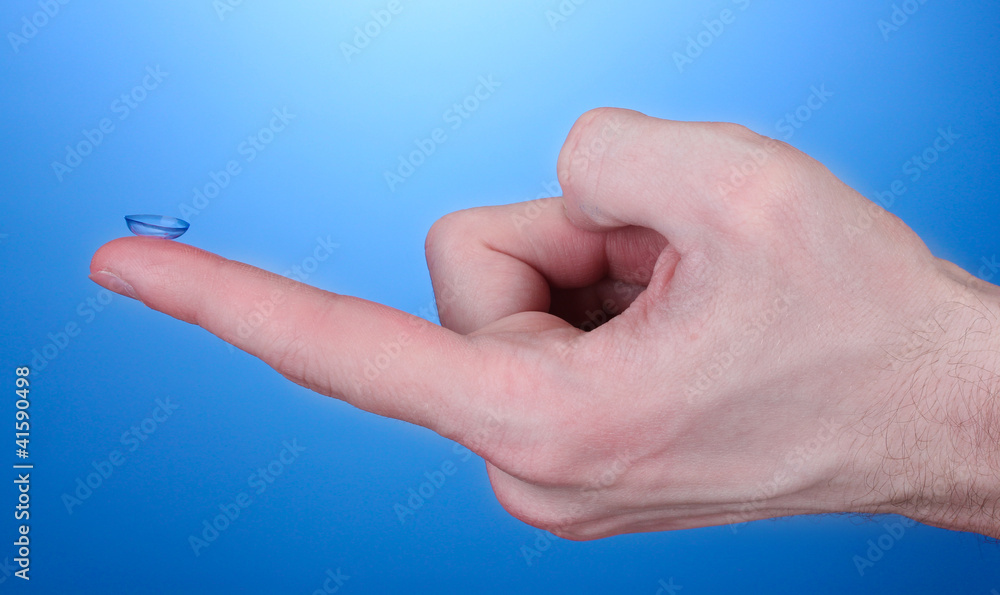 contact lens on finger on blue background contact lens on finger on blue background