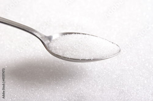Sugar on a spoon in sugar background