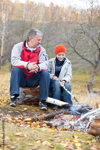 Grandfather and grandson around a campfire