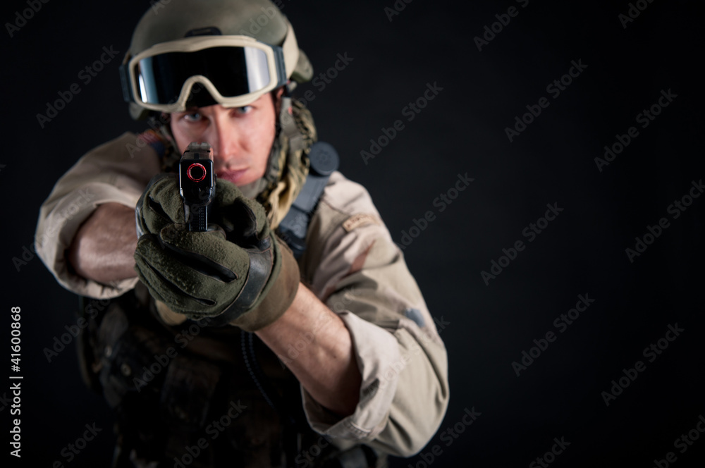 Soldier with gun against black background.