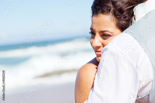young woman hugging husband on beach