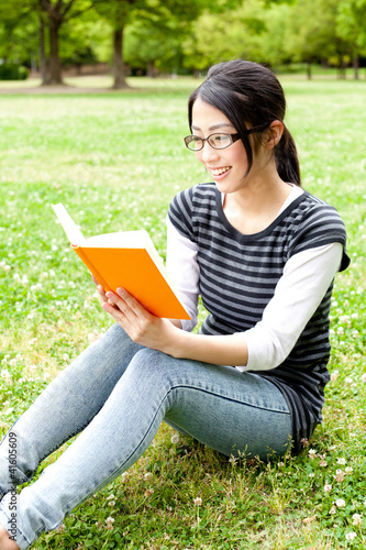 asian woman reading a book in the park
