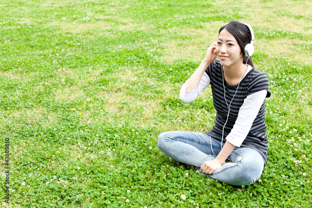 attractive asian woman listening to music in the park