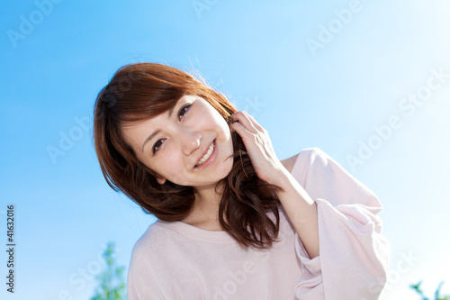 Beautiful young woman outdoors over blue sky. Portrait of asian