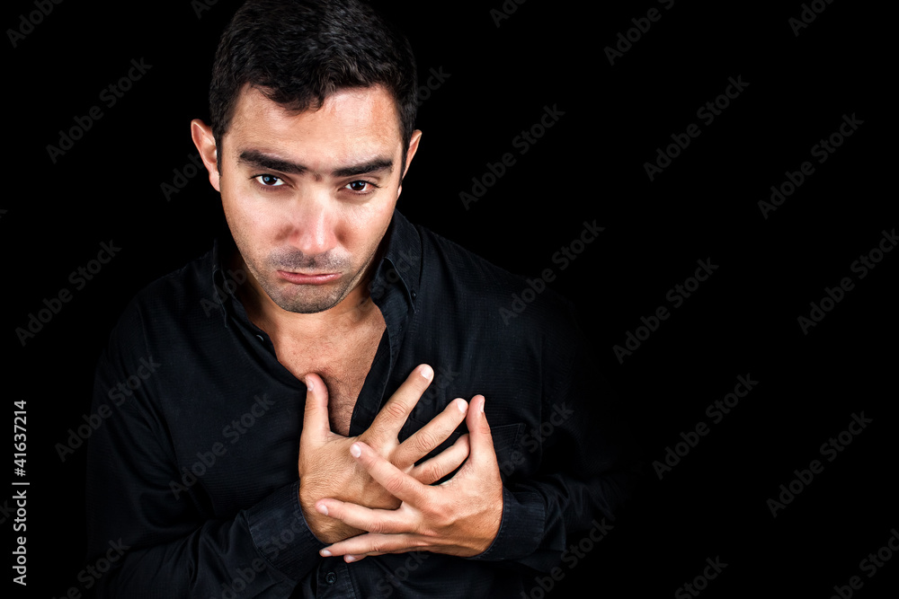 Young man having a heart attack isolated on black