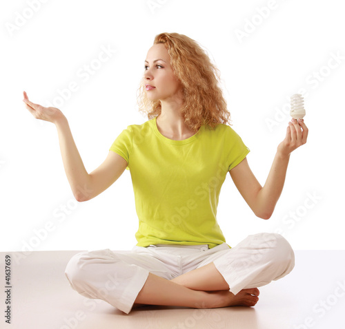 Woman with energy-saving bulb sitting cross-legged on floor.