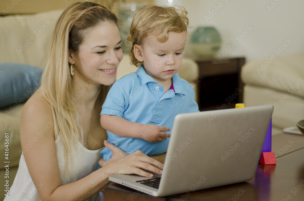Cute young mother showing her son something in a laptop Cute young mother showing her son something in a laptop