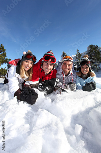 Four friends laying in the snow