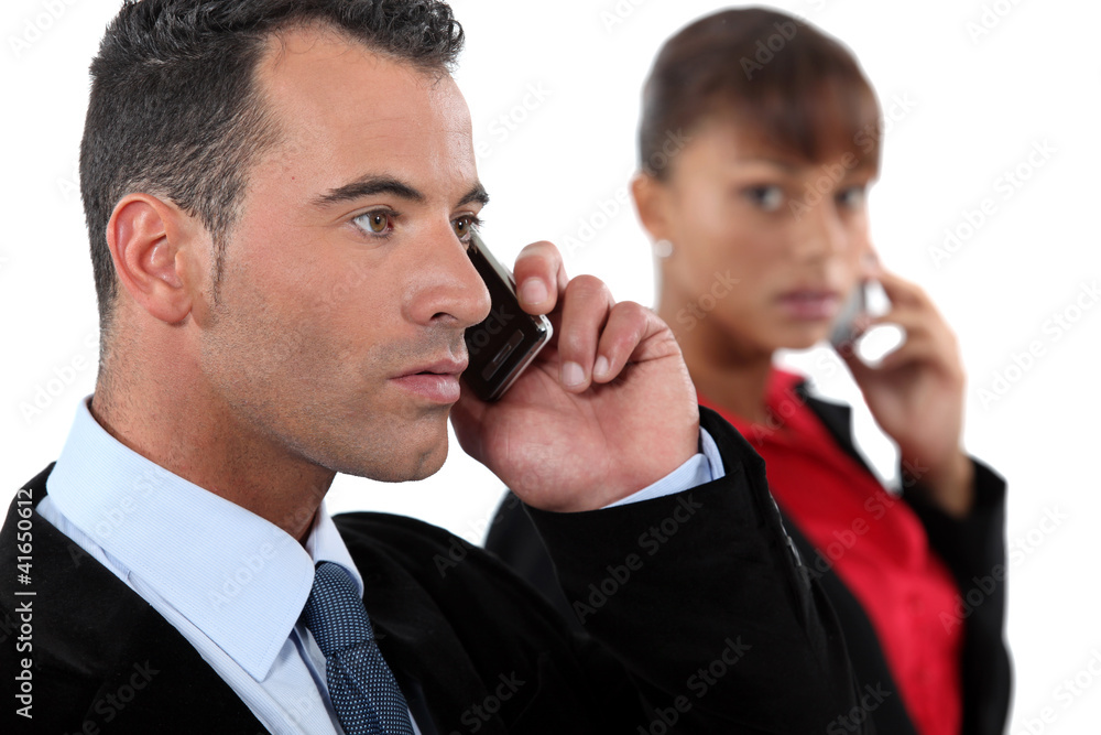 businessman making a call and female colleague behind businessman making a call and female colleague behind