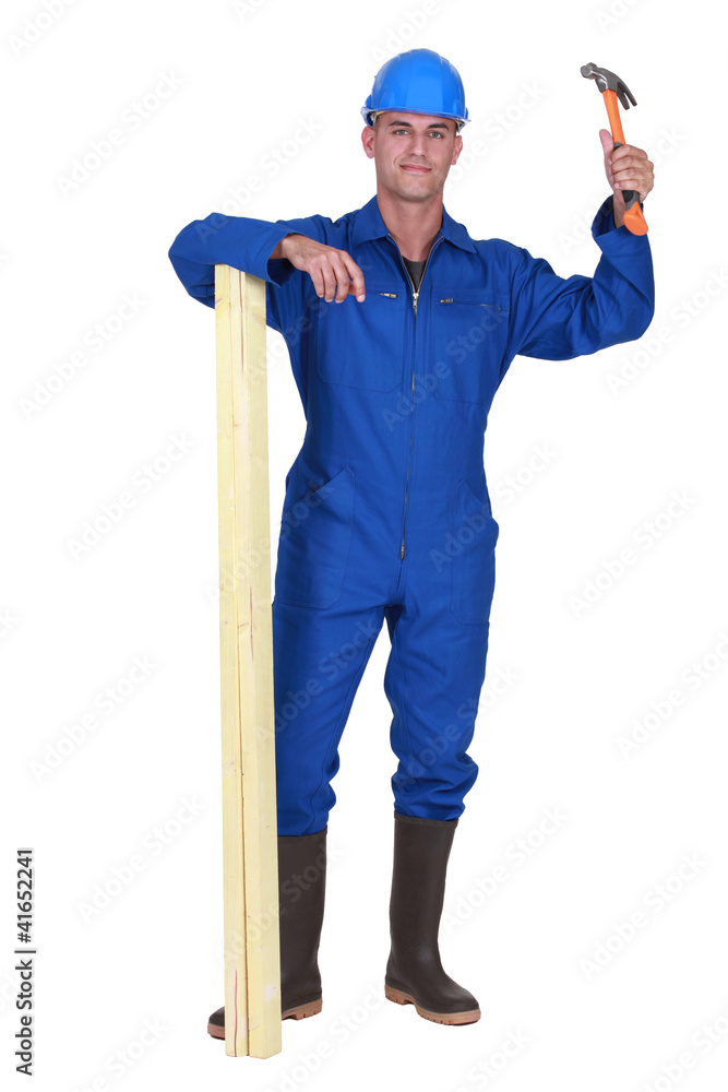 A male carpenter with a hammer and a plank. A male carpenter with a hammer and a plank.