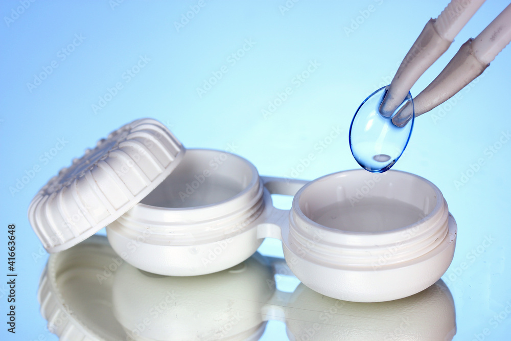 contact lenses in containers and tweezers on blue background contact lenses in containers and tweezers on blue background