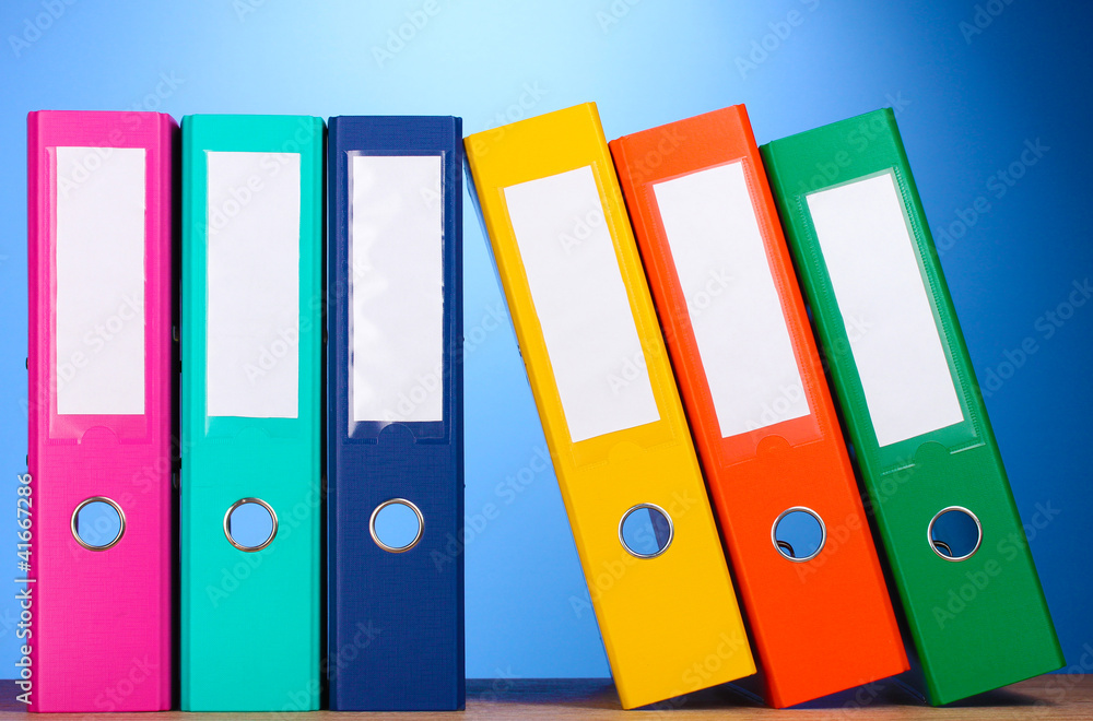 bright office folders on wooden table on blue background bright office folders on wooden table on blue background