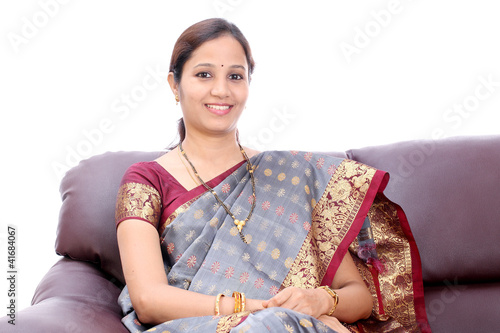 Smiling young Indian woman sitting in sofa photo