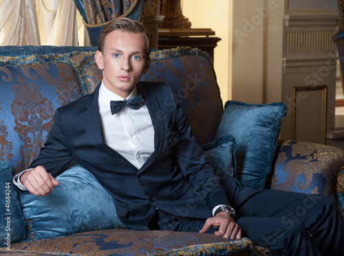 Young blond man with blue eyes in luxury interior photo