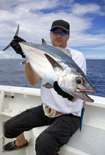 Happy  fisherman holding a tuna fish photo