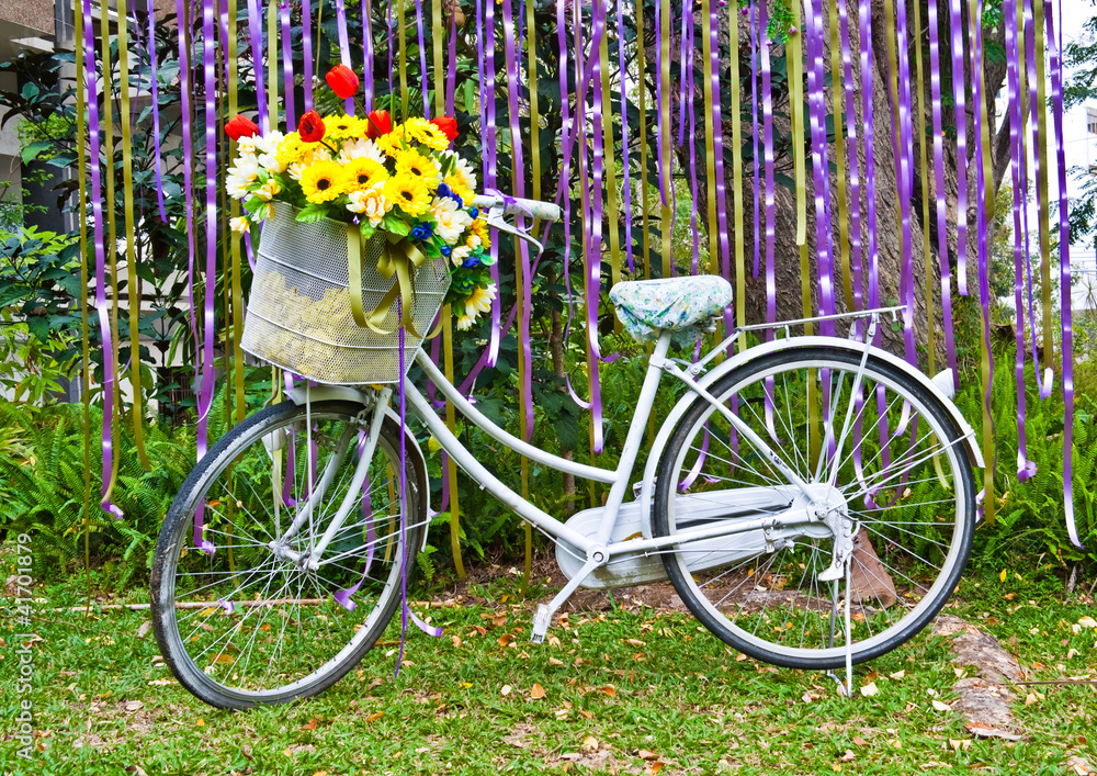 decorative old white painted  bicycle with basket of colorful fl
