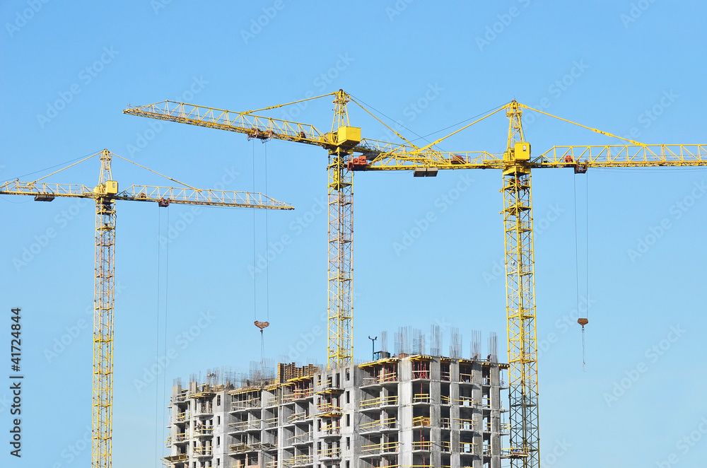 Building crane and building under construction against blue sky Building crane and building under construction against blue sky