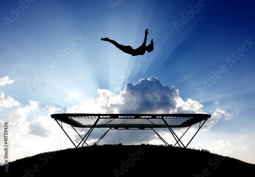 silhouette of female gymnast on trampoline in sky