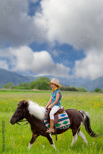 Horseback riding - lovely cowgirl is riding a pony