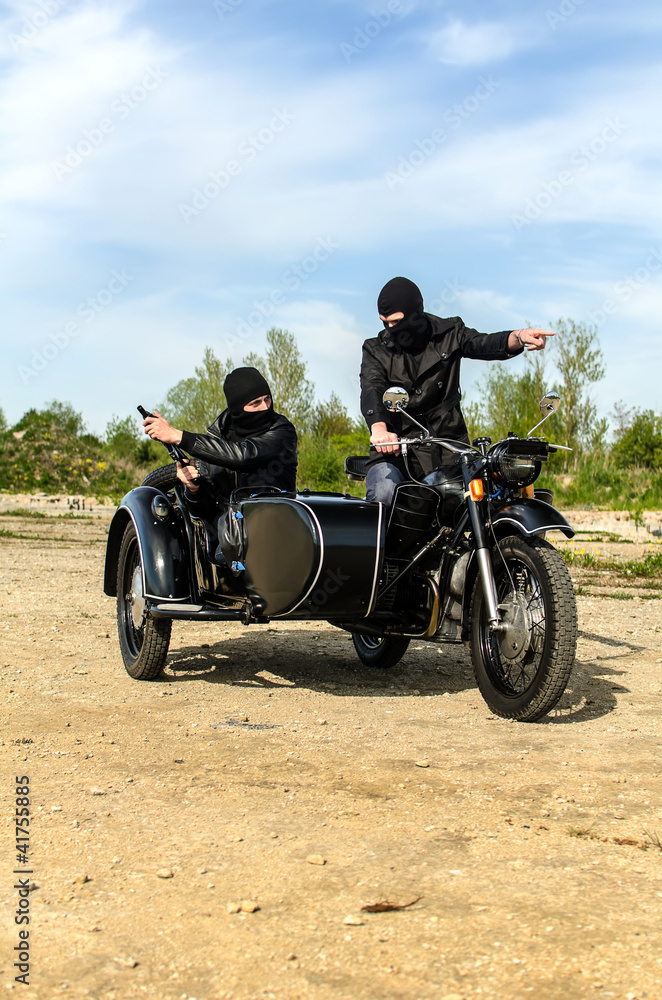 Fototapeta premium Two armed men riding a motorcycle with a sidecar