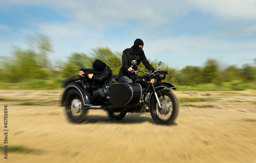 Two armed men riding a motorcycle with a sidecar. Motion blur. Two armed men riding a motorcycle with a sidecar. Motion blur.