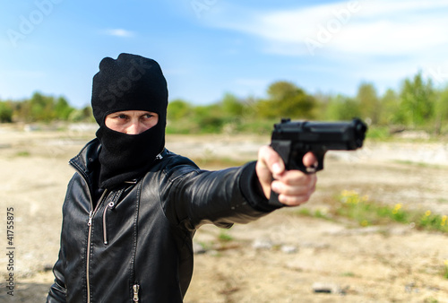 Masked gunman taking aim with a gun