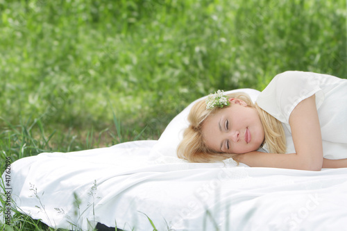 young beautiful woman sleeping on white bed on natural backgroun