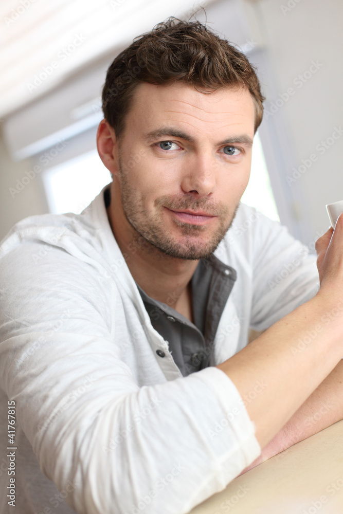 Portrait of handsome guy drinking coffee in home kitchen Portrait of handsome guy drinking coffee in home kitchen
