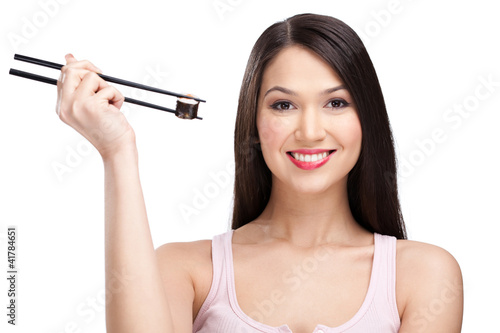 Smiling woman holding sushi roll with a chopsticks