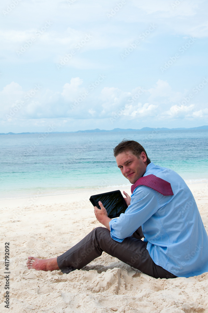 Business man sitting on the beach with tablet computer