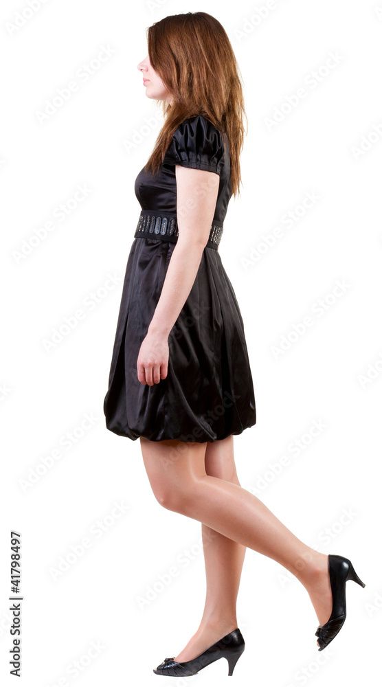 back view of walking  brunette woman  in black dress