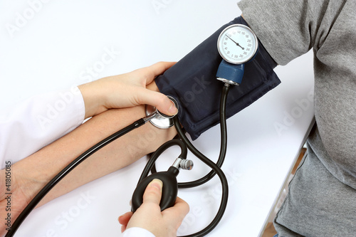 Doctor checking blood pressure with stethoscope and sphygmomanom photo