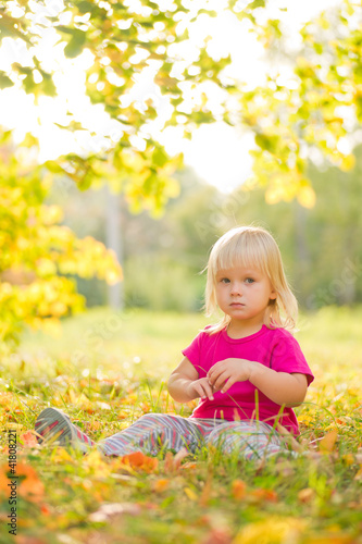 Adorable baby sit on grass with leaf under trees shadow on sunse