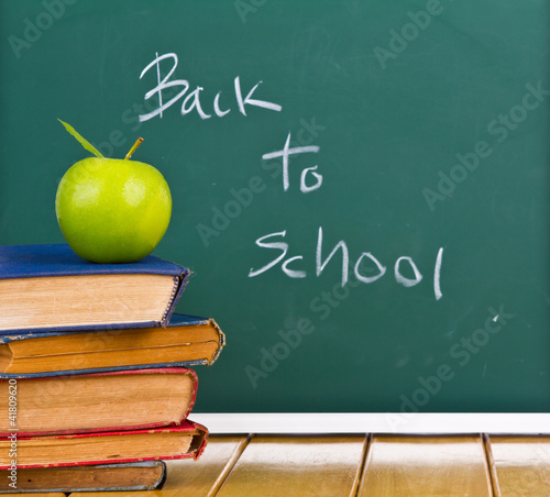 Back to school written on chalkboard with green apple and books