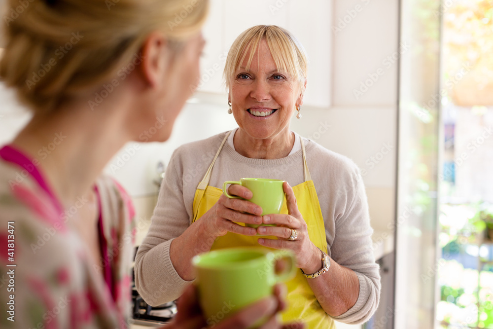 Mother and daughter talking, drinking coffee in kitchen Mother and daughter talking, drinking coffee in kitchen