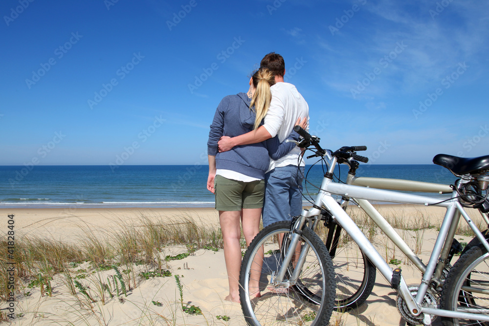 Couple standing on a sand dune with bicycles