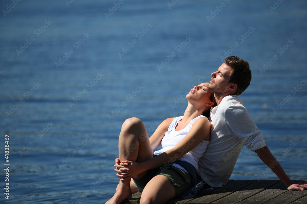 Couple relaxing on a lake bridge in summertime