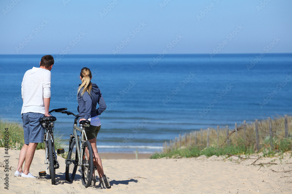 © goodluz - Couple with bicycles looking at the ocean
