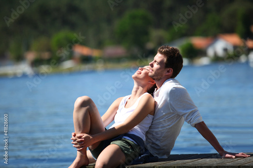 Couple relaxing on a lake bridge in summertime