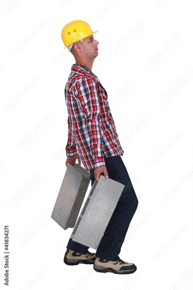 Man carrying two heavy building blocks Man carrying two heavy building blocks